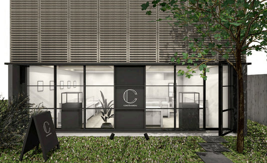 Modern storefront of CONTÉVANOU with large glass windows, black frames, display cases, and greenery outside
