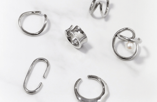 Contévanou collection of silver rings featuring unique, modern designs and a pearl accent on white background