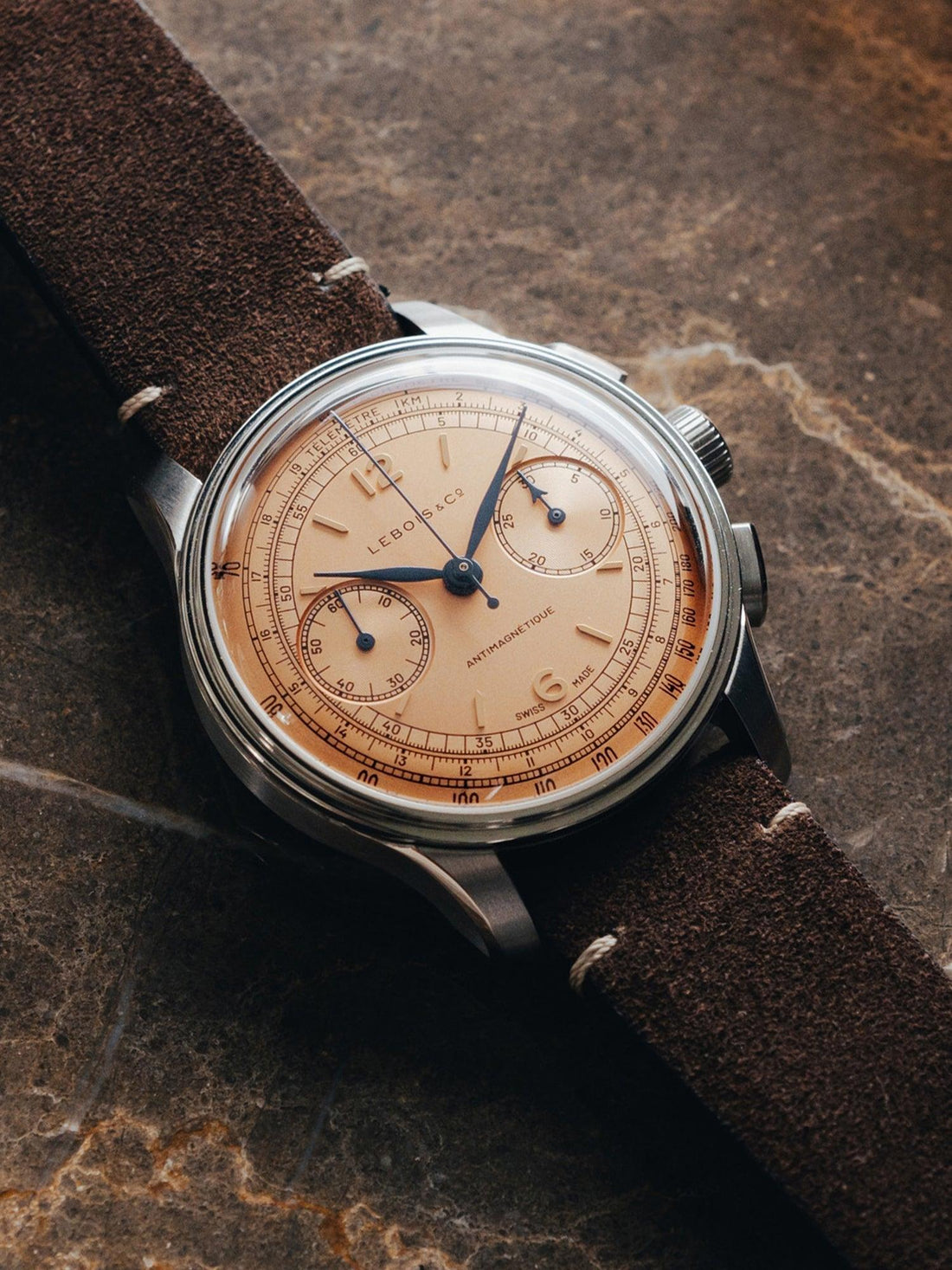 Contévanou vintage Lebois & Co chronograph wristwatch with salmon dial and brown suede strap on stone surface