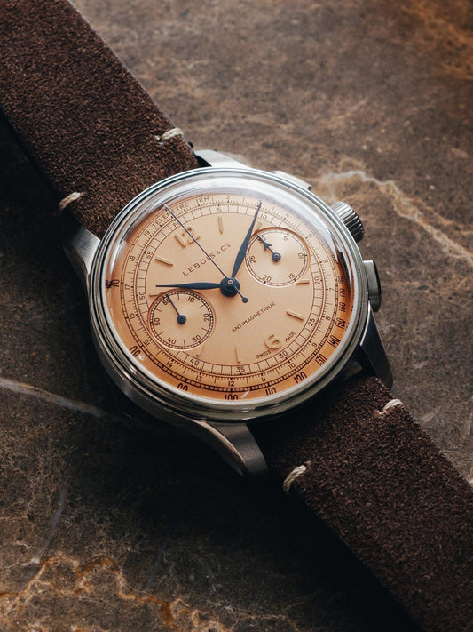 Contévanou vintage Lebois & Co chronograph wristwatch with salmon dial and brown suede strap on stone surface