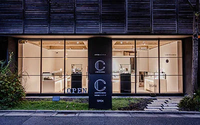 Contévanou boutique exterior at night with illuminated display windows showcasing watches and jewelry in a calm urban setting