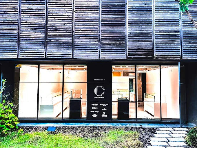 木製外壁の時計宝飾店、店内にブランドロゴとディスプレイが見える。機械式時計、腕時計、宝飾品専門店。