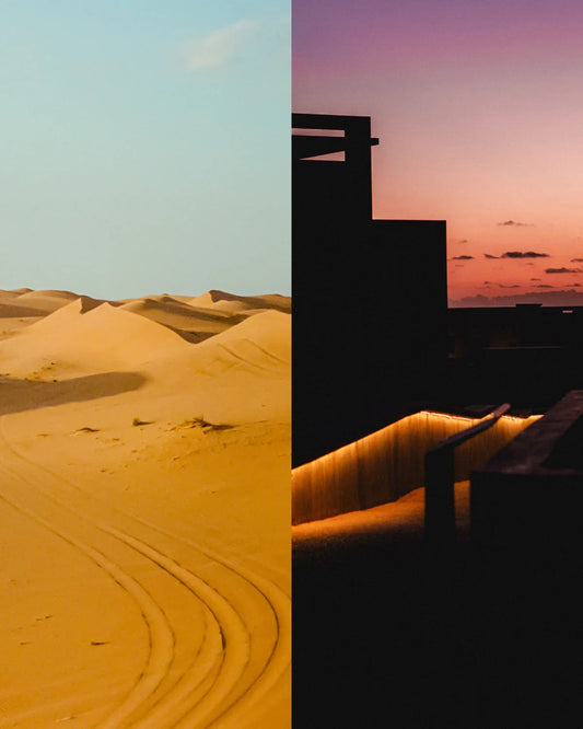 砂漠の砂丘と夕焼け空、建物のシルエットと温かみのある照明