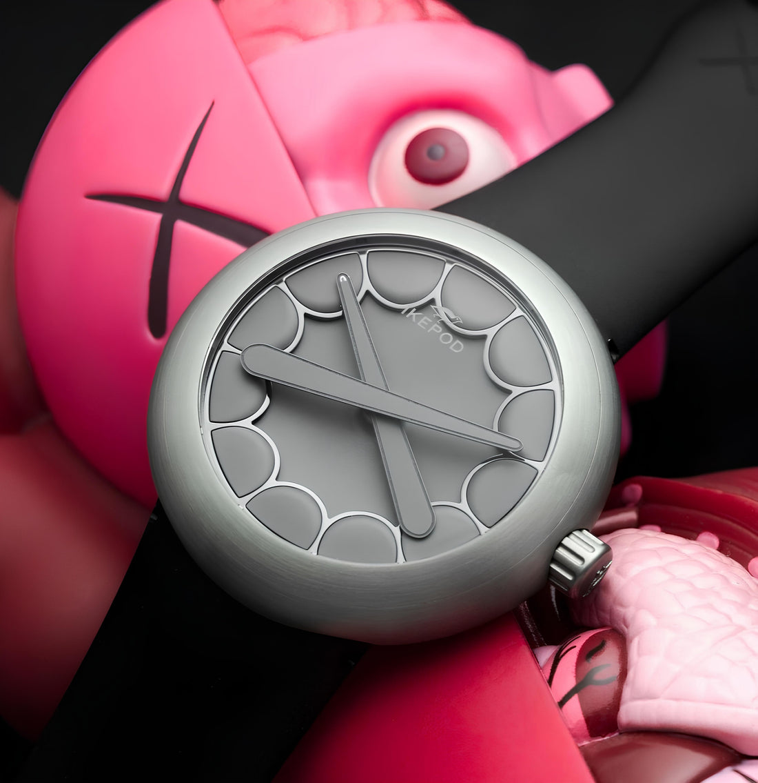 IKEPOD mechanical wristwatch with unique scalloped gray dial and black strap on pink designer art toy