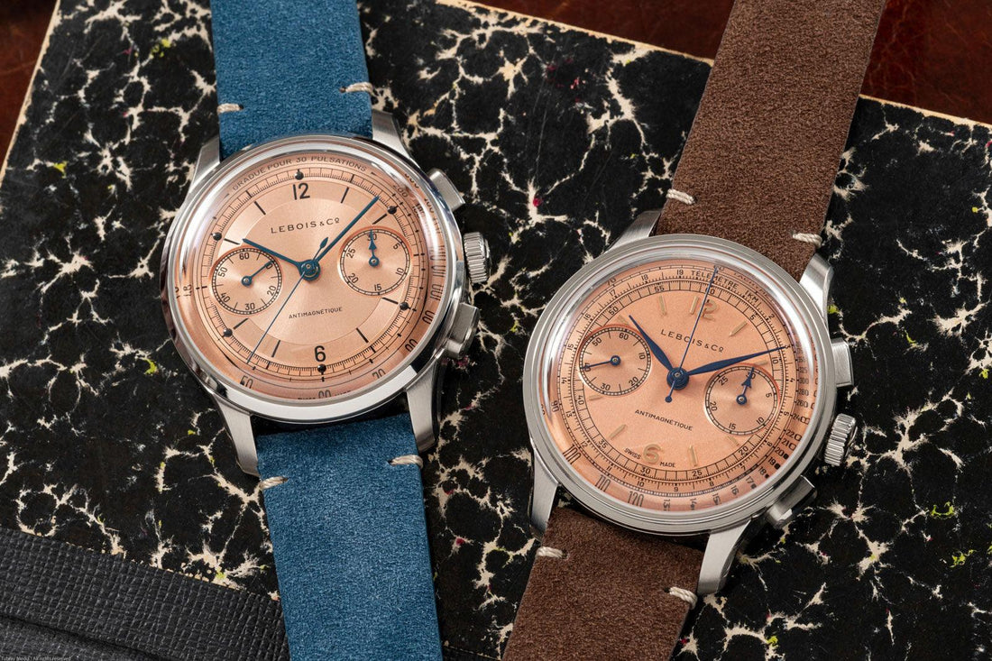 Two Contévanu vintage-style Lebois & Co Heritage Chronograph watches with salmon dials, blue and brown suede straps on a marble patterned surface