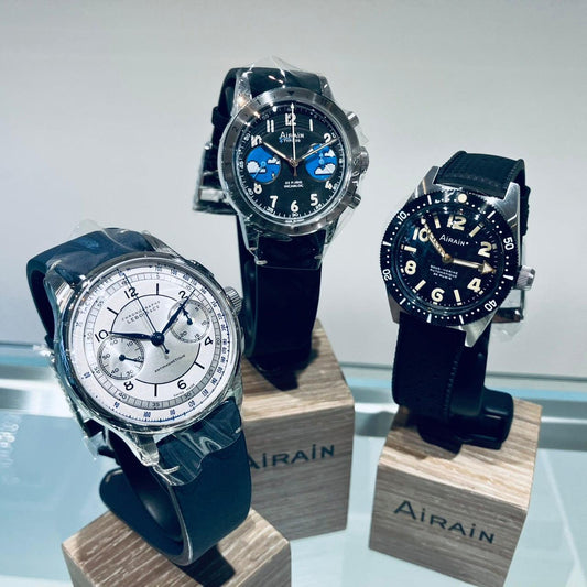 Three Airain mechanical wristwatches with black straps displayed on wooden stands at コントワーヌ watch store