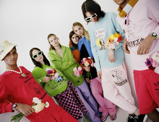 Diverse models in colorful streetwear holding flowers, showcasing bold, artistic fashion styles