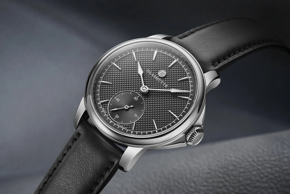 Luxury mechanical wristwatch with textured black dial, subdial, and black leather strap on display